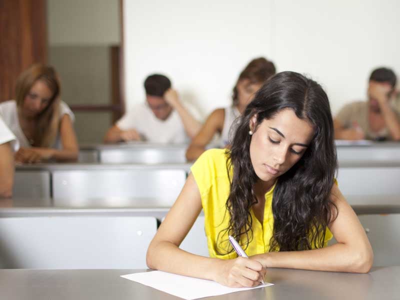 Estudiantes concentrados presentando el examen de admisión UNAM 2025 en un aula.