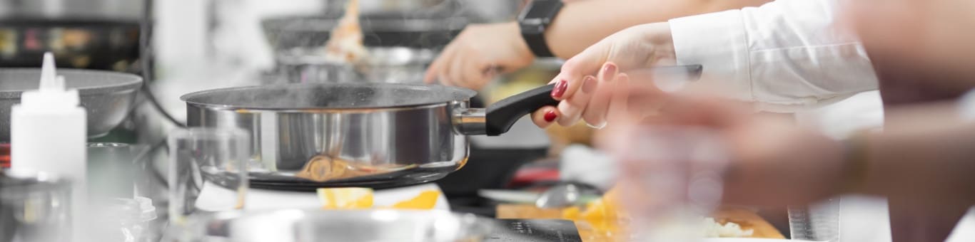 Estudiantes de gastronomía preparando alimentos en cocina profesional durante clase práctica