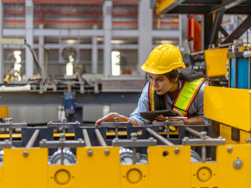Ingeniera mecánica supervisando maquinaria industrial en planta de producción