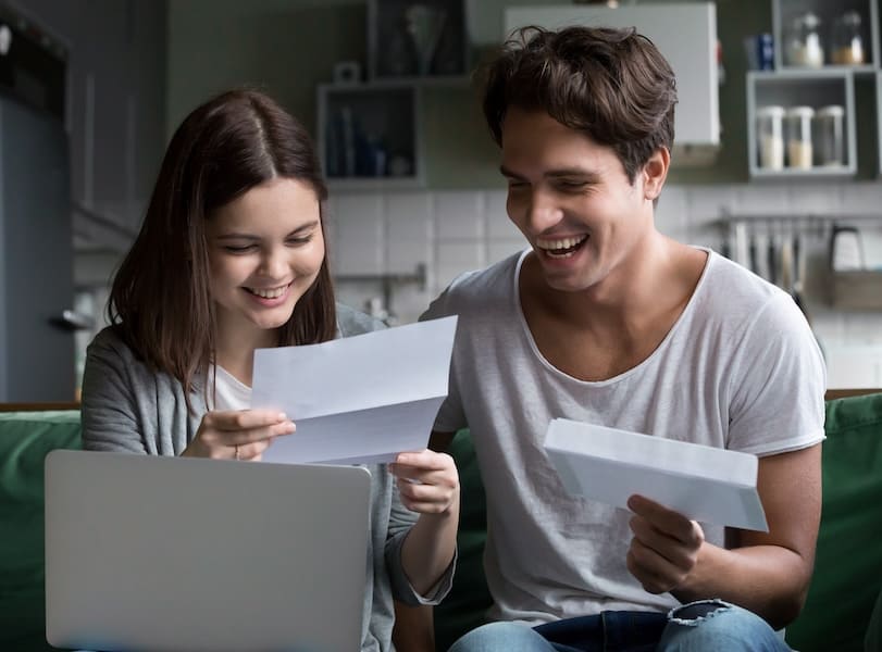 Pareja de estudiantes sonriendo al recibir su carta de admisión a la preparatoria