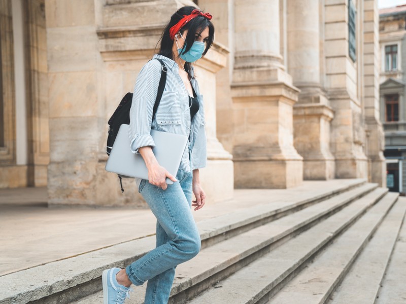 revalidar_materias_de_universidad_mujer_joven_sale_de_universidad_cargando_computadora
